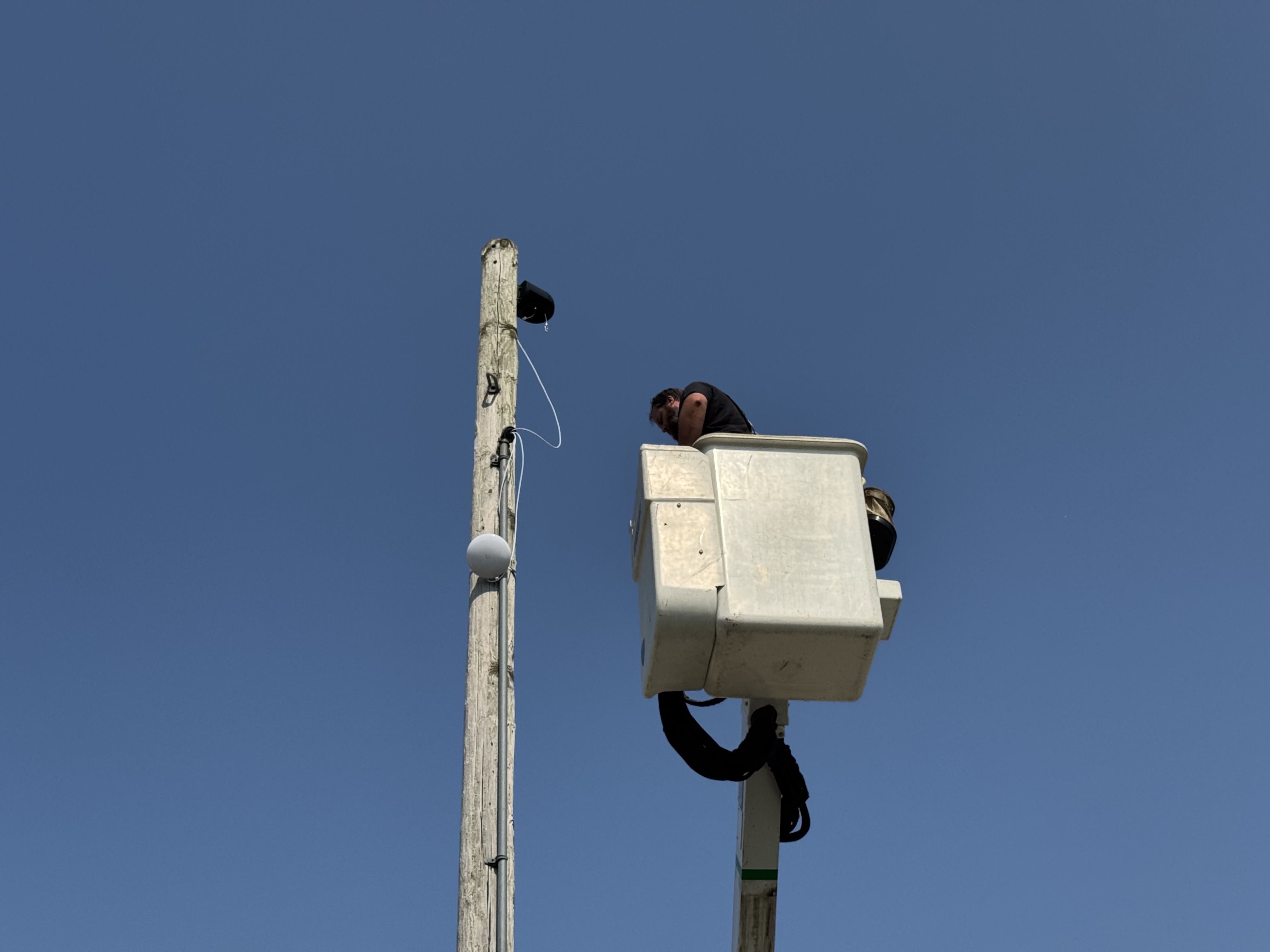 A technician in a bucket lift installing a camera on a pole